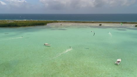 Drone-Shot-Océano-Y-Naturaleza-Rodean-Cuatro-Hombres-Kiteboard-Mar-Caribe,-Salinas-Los-Roques