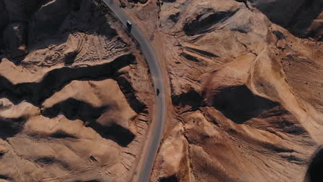 Drone-shot-of-a-desert-mounts,-riding-cars-and-trucks-on-a-road,-Jurassic-park-look,-blue-sky