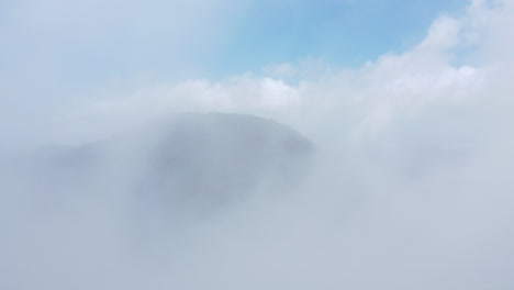 Hoher-Berg-Mit-Durch-Die-Wolken-Und-Einem-Dichten-Wald-Drumherum,-Atemberaubender-Blick-über-Die-Wolken