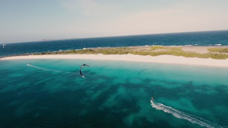Men-kitesurfing-along-white-sand-beach,-aerial-view-Crasqui-island-los-Roques