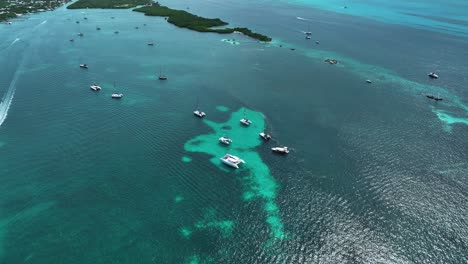 Aerial-view-over-catamarans-in-turquoise-waters,-of-Isla-Mujeres,-Mexico---tilt,-drone-shot