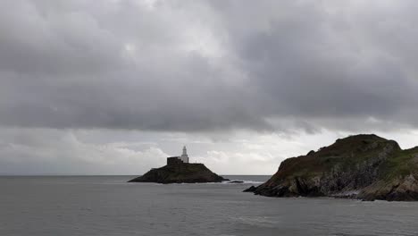 Island-Lighthouse-in-Mumbles-with-Dramatic-Cloudscape-on-Windy-Day---Camera-Pannng-Shot-4K