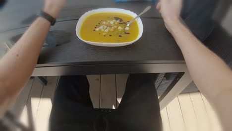 POV-first-person-eating-orange-pumpkin-soup-outside