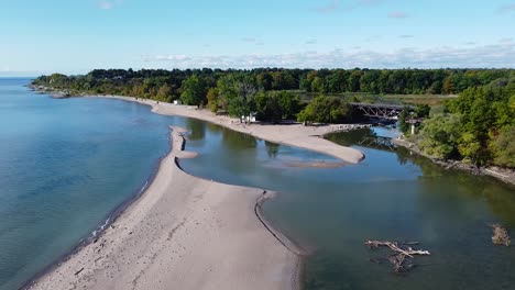 Lake-Ontario-freshwater-shoreline-beach-with-birds,-train-bridge-and-river