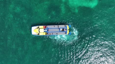 Aerial-view-above-a-ferry-in-calm-waters-of-the-Caribbean---rotating,-top-down,-drone-shot