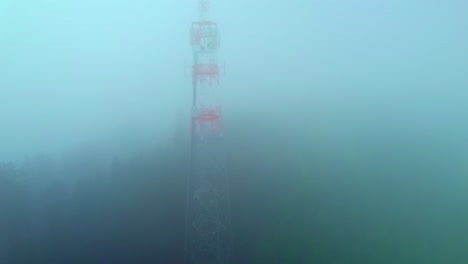 A-transmission-tower-in-the-middle-of-a-dense-forest-on-a-foggy-autumn-morning