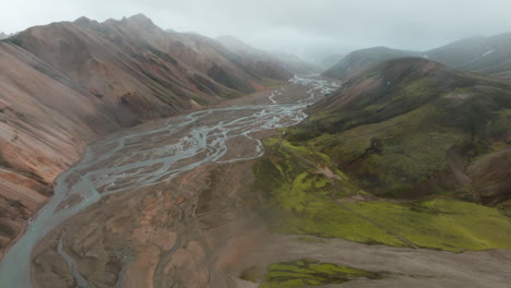 Aerial-tracking-shot-looking-down-misty-river-valley,-Landmannalaugar,-Iceland