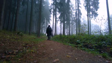 Man-with-a-backpack-travels-alone-through-a-foggy-forest-on-a-cold-autumn-morning
