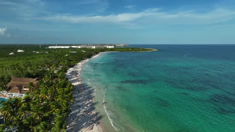 Aerial-view-over-a-beach-and-shallow,-turquoise-water-in-sunny-Xpu-Ha,-Mexico