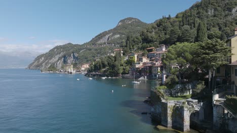 4K-Aerial---Slow-push-in-past-the-headland-to-reveal-Varenna,-Lake-Como,-Italy