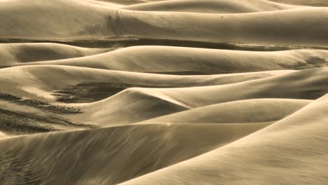 Strong-wind-blows-sand-over-surface-of-dunes,-aerial-trucking---nature-spectacle