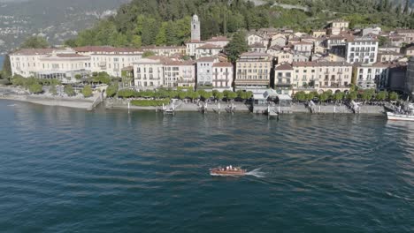 4K-Aerial---Pull-back-from-a-classic-boat-in-Lake-Como,-Italy-to-reveal-Bellagio,-Lake-Como,-Italy
