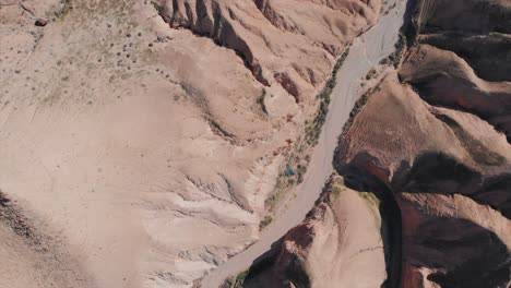 Flying-Drone-shot-above-a-dry-lake-in-a-desert-between-mounts,-Jurassic-park-look,-blue-sky