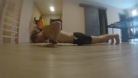Home-gym-workout-teenage-man-doing-push-ups-in-shorts-no-t-shirt-fitness