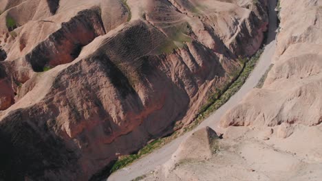 Drone-tilt-down-shot-of-a-desert-green-mounts,-Jurassic-park-look,-blue-sky