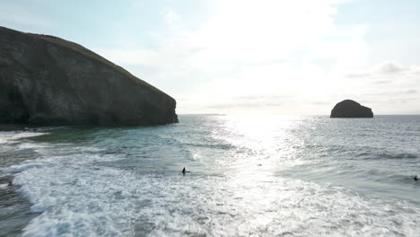 Trebarwith-beach,-Cornwall,-aerial-flight-across-beautiful-sea-into-sunlight-to-headland-cliffs---mavic-3-cine-prores-422---Clip-2
