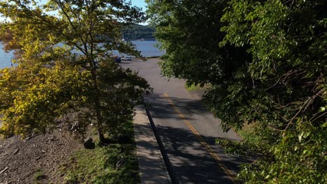 An-aerial-view-of-an-empty-two-lane-road-leading-to-a-boat-dock-in-upstate,-NY-on-a-sunny-morning