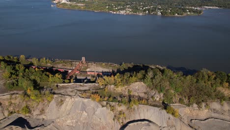 An-aerial-view-over-train-tracks-as-a-long-cargo-train-goes-by-next-to-the-Hudson-River-in-upstate-NY