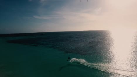 Man-kitesurf-along-beach-at-sunset-against-light-,-jump-and-sail-in-Los-Roques