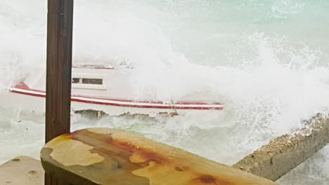 Close-up-slowmotion-shot-of-local-wooden-fishing-boat-being-smashed-into-pieces-during-sudden-storm-with-rough-waves,-Caribbean