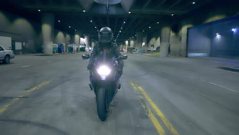 A-woman-rides-her-motorcycle-towards-the-camera-on-a-quiet-underground-street-in-Los-Angeles,-CA