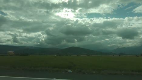 Vista-Desde-La-Ventana-Del-Auto-Con-Una-Hermosa-Puesta-De-Sol-Nublada-Entre-Montañas-Hd