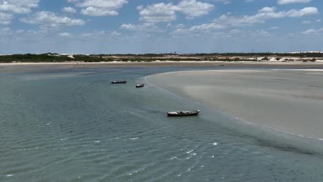 Aerial-Drone-Fly-Above-Jericoacoara-Calm-Blue-Beach-Still-Waves,-Boats,-Brazil-Traveling-Destination,-Tropical-Desert-Dunes-in-Northeastern-Latin-America
