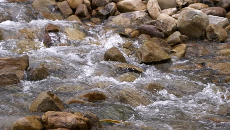 Clear-stream-running-through-stone-boulders-Abundant-river-flowing-in-slow-motion