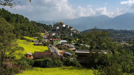 Una-Vista-De-Lapso-De-Tiempo-De-Zoom-Del-Monasterio-Neydo-Tashi-Choling-En-La-Pequeña-Ciudad-De-Dakshinkali-En-Nepal-Rodeada-De-Campos-De-Mostaza