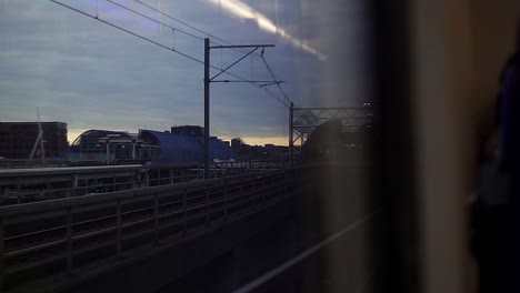 Zugfahrgastsicht-Durch-Fenster-über-Gleise-Und-Bahnhof