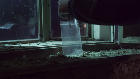 Putting-keys-or-keychain-into-plastic-bag,-crime-scene-investigation-close-up-view-at-night