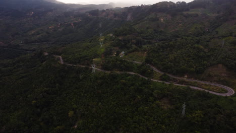 Winding-asphalt-road-leading-up-to-Vietnamese-highlands-through-jungle-landscape,-aerial-view
