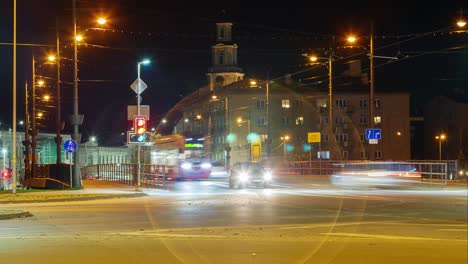 Timelapse-of-city-rush-hour-traffic-on-the-street-of-Liepaja-tram-bridge,-traffic-light-streaks,-tram-rails-with-fast-moving-trams,-medium-wide-shot