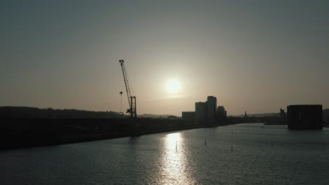 Flying-near-crane-on-harbour-during-sunset