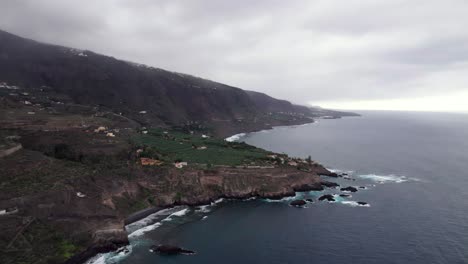Banana-plantation-on-rocky-coastline-Tenerife,-aerial-tilt-up-reveal