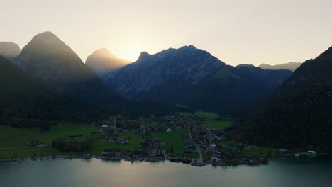 Kleines-Dorf-Pertisau-Am-Achensee-Mit-Sonnenaufgang-Silhouette-Der-Tiroler-Region-Alpine-Bergkette-Schwenkluftaufnahme