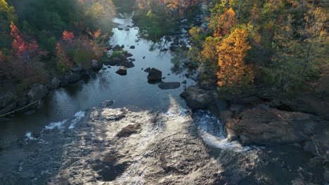 Felsiger-Fluss-Mit-Herbstwäldern-An-Den-Seiten-Und-Dem-Sonnenlicht-Direkt-Vorne
