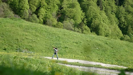Zoom-shot-of-millennial-caucasian-backpacker-hiking-on-rural-mountain-trail