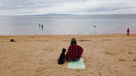 Frau-Sitzt-Allein-Mit-Ihrem-Hund-Am-Strand,-Ruhige-Meditation,-Starrt-Auf-Das-Meer-Am-Wunderschönen-Sanur-Beach,-Indonesien