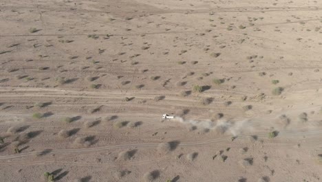 An-aerial-view-of-a-white-truck-driving-along-a-dirt-road