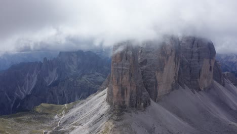 Aerial-wide-shot-of-Three-Merlons-covered-by-dense-clouds-at-sky---Dolomites,-Italy