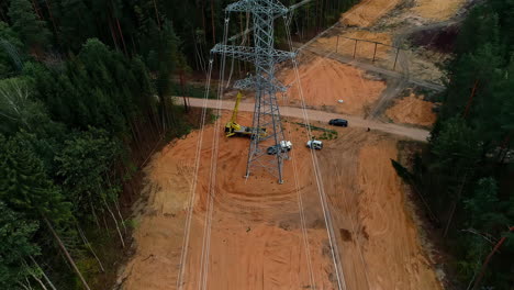 Newly-erected-high-capacity-electrical-transmission-tower-through-a-wilderness-forest---aerial-tilt-up-reveal