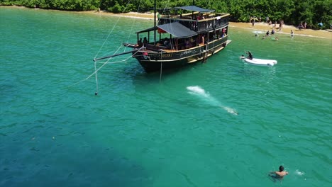 Girl-Diving-off-of-a-Pirate-ship-set-anchor-off-Coast-of-Island-in-Crystal-Clear-Water-in-Brazilian-Ocean