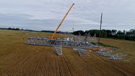 Crane-and-crew-erecting-a-electrical-transmission-powerline-pylon-in-the-European-countryside---orbiting-aerial-view