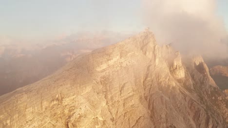 Aerial-forward-flight-towards-Cinque-Torri-Mountains-during-foggy-day-at-sunset