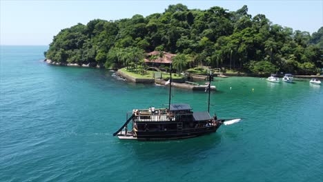 Pirate-Ship-Tour-above-Crystal-Clear-Reef-in-Brazilian-Ocean-pulling-up-to-Island