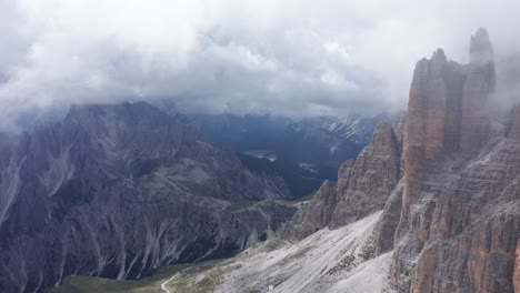 Aerial-drone-shot-of-mysterious-clouds-hovering-around-Tre-Cime-spires-in-the-Dolomites