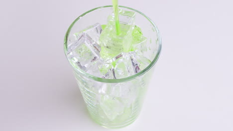 Pouring-soft-Drinks-and-green-soda-into-Glass-Isolated-o-White-Background