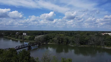 Drone-footage-over-a-field,-over-a-river,-and-into-a-small-Midwest-town