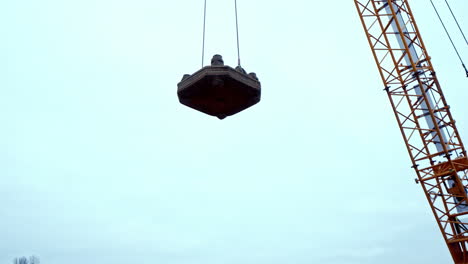 A-crane-lifts-a-drops-a-flat-weight-for-dynamic-soil-compaction-at-a-construction-site